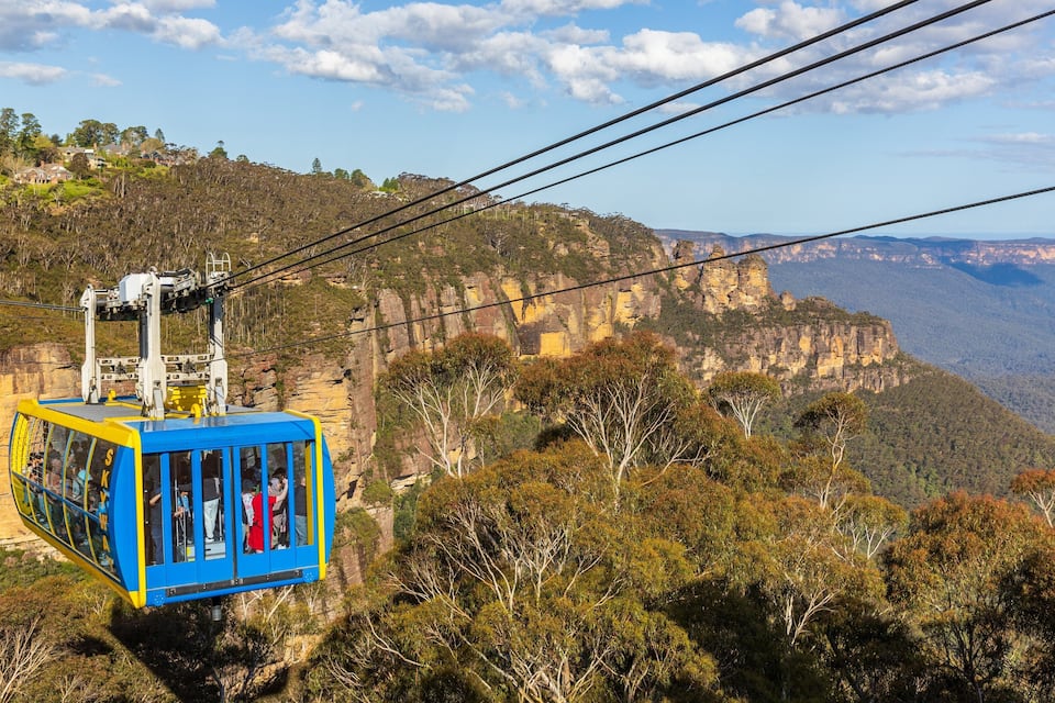 Une télécabine transportant des passagers, un paysage montagneux et un ciel dégagé.