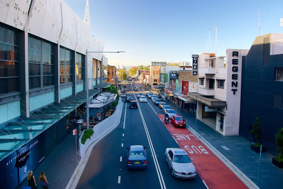 A city street with cars, a bus lane, and modern buildings.