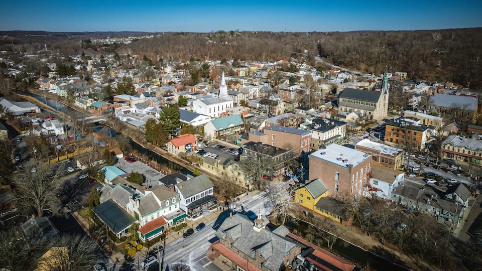An aerial view of a town with a prominent church, a river, and a mix of residential and commercial buildings.