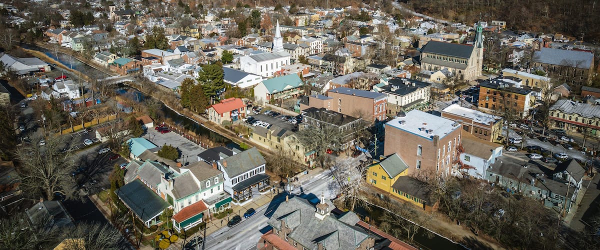 An aerial view of a town with a prominent church, a river, and a mix of residential and commercial buildings.