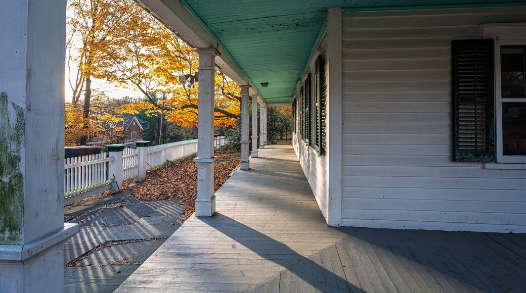 Sunlit view of Ambler Farm porch with autumn foliage in Wilton CT