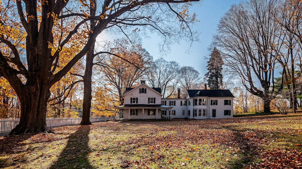A large house surrounded by trees and a grassy yard.