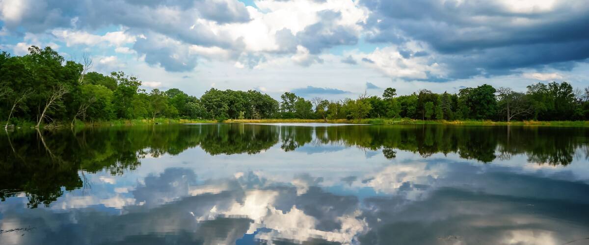 A lake view with the sky reflecting off the still surface at Independence Grove Forest Preserve in Libertyville, Illinois USA.