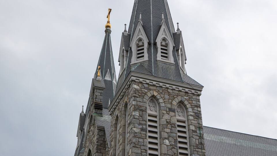 A Gothic-style church with a pointed steeple and a golden statue on top.