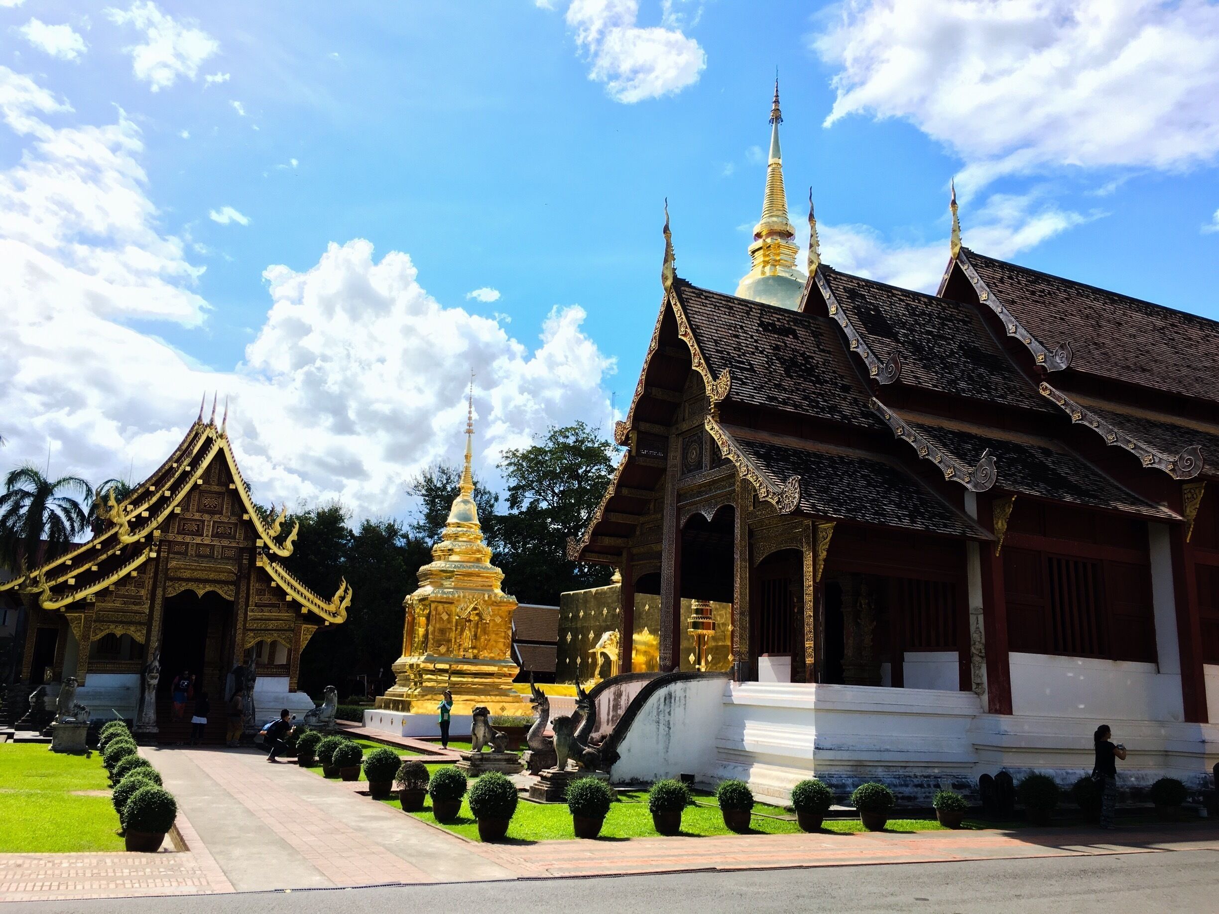 A traditional temple complex with ornate golden structures and a white building with a tiled roof.