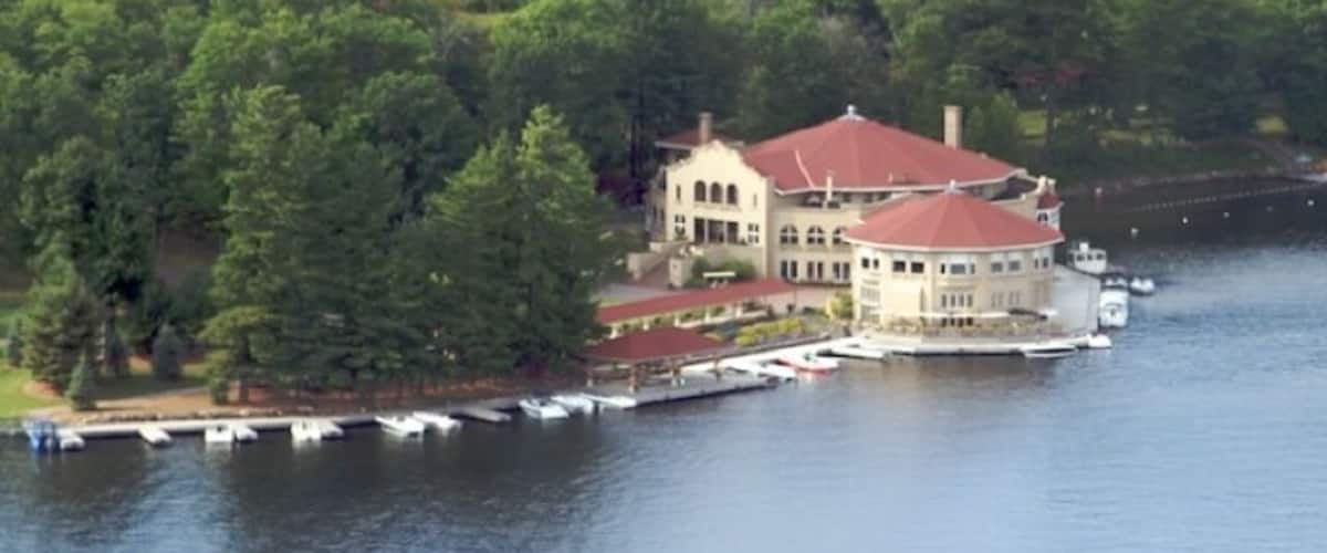 A lakeside property with a large house surrounded by dense forest.