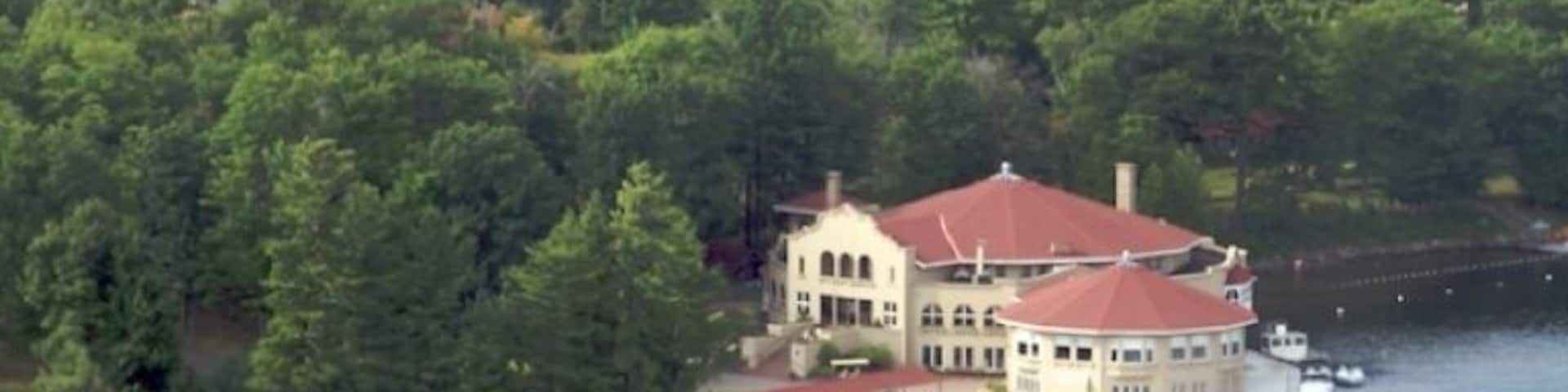 A lakeside property with a large house surrounded by dense forest.