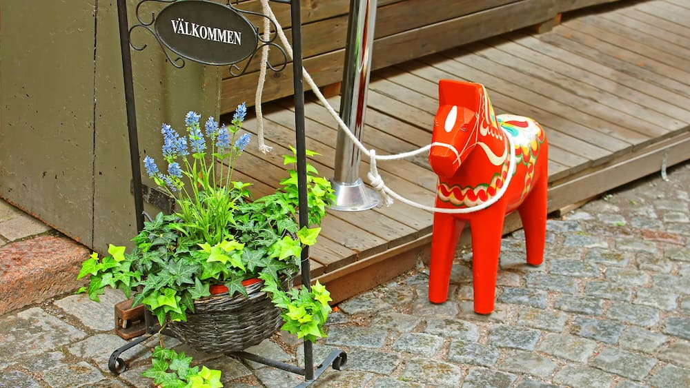 Inscription "Welcome" and a hand-made traditional wooden Dalecarlian Horse at the entrance to the little shop in Gamla Stan, Stockholm, Sweden