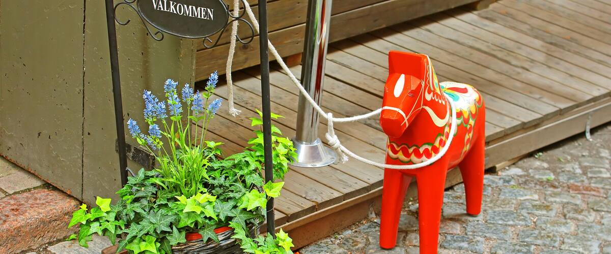 Inscription "Welcome" and a hand-made traditional wooden Dalecarlian Horse at the entrance to the little shop in Gamla Stan, Stockholm, Sweden