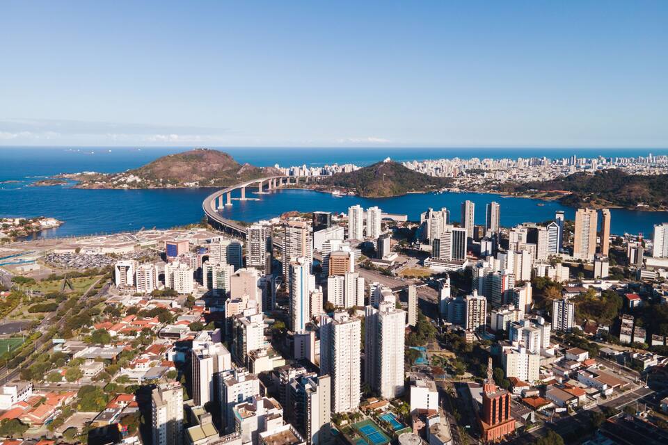 A coastal cityscape with high-rise buildings, a bridge, and a bay.
