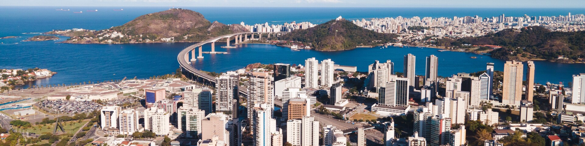 Imagem aérea da cidade de Vitória, mostrando a ponte, o centro, a Reta da Penha, Enseada do Suá, Bahia de Vitória e o Shopping Vitória.