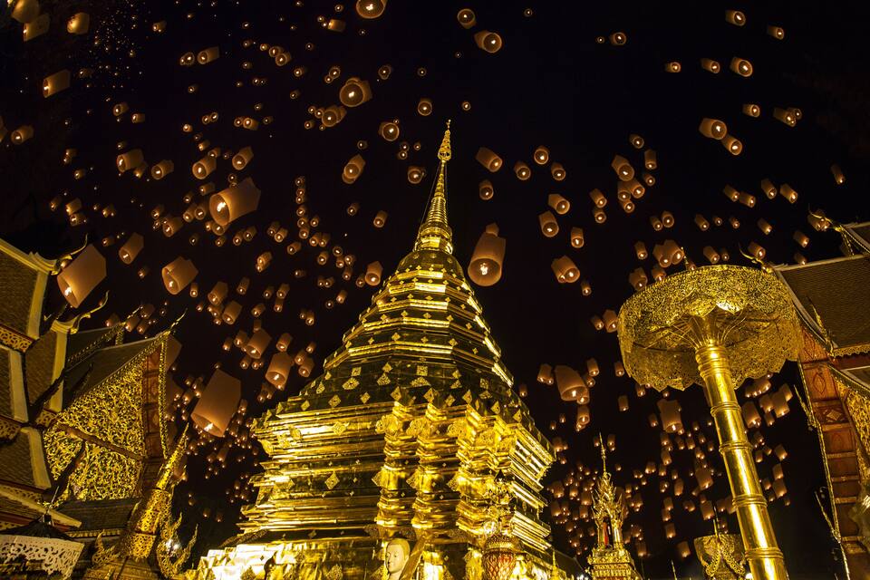 A golden temple with intricate carvings and a pointed spire, surrounded by numerous floating lanterns.