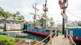 Eine piratenthematische Wasserattraktion mit einem großen Schiff, einem kleinen Boot und einem Rettungsboot.