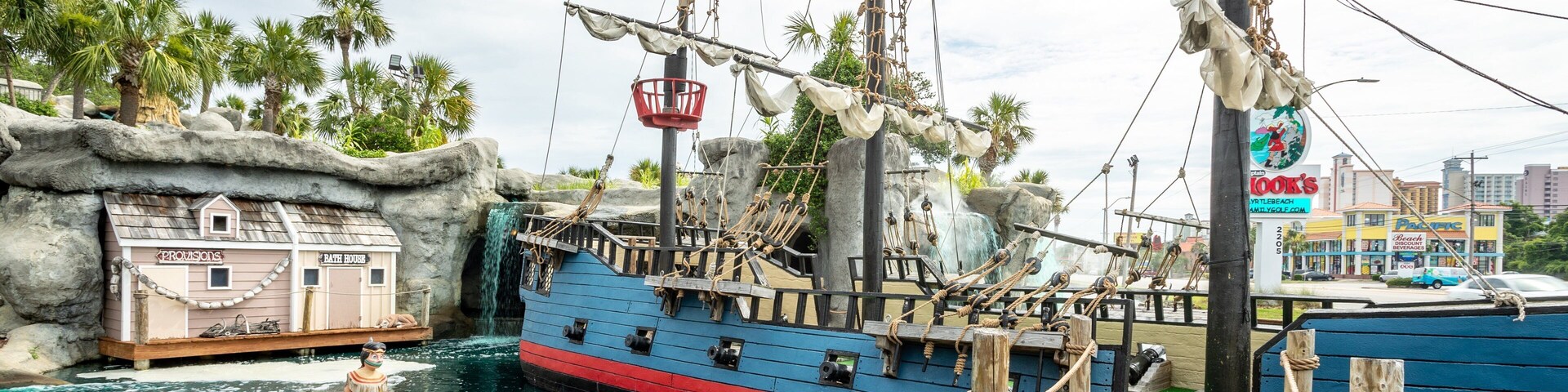 Uma atração aquática com tema de pirata, apresentando um navio grande, um barco pequeno e um bote salva-vidas.