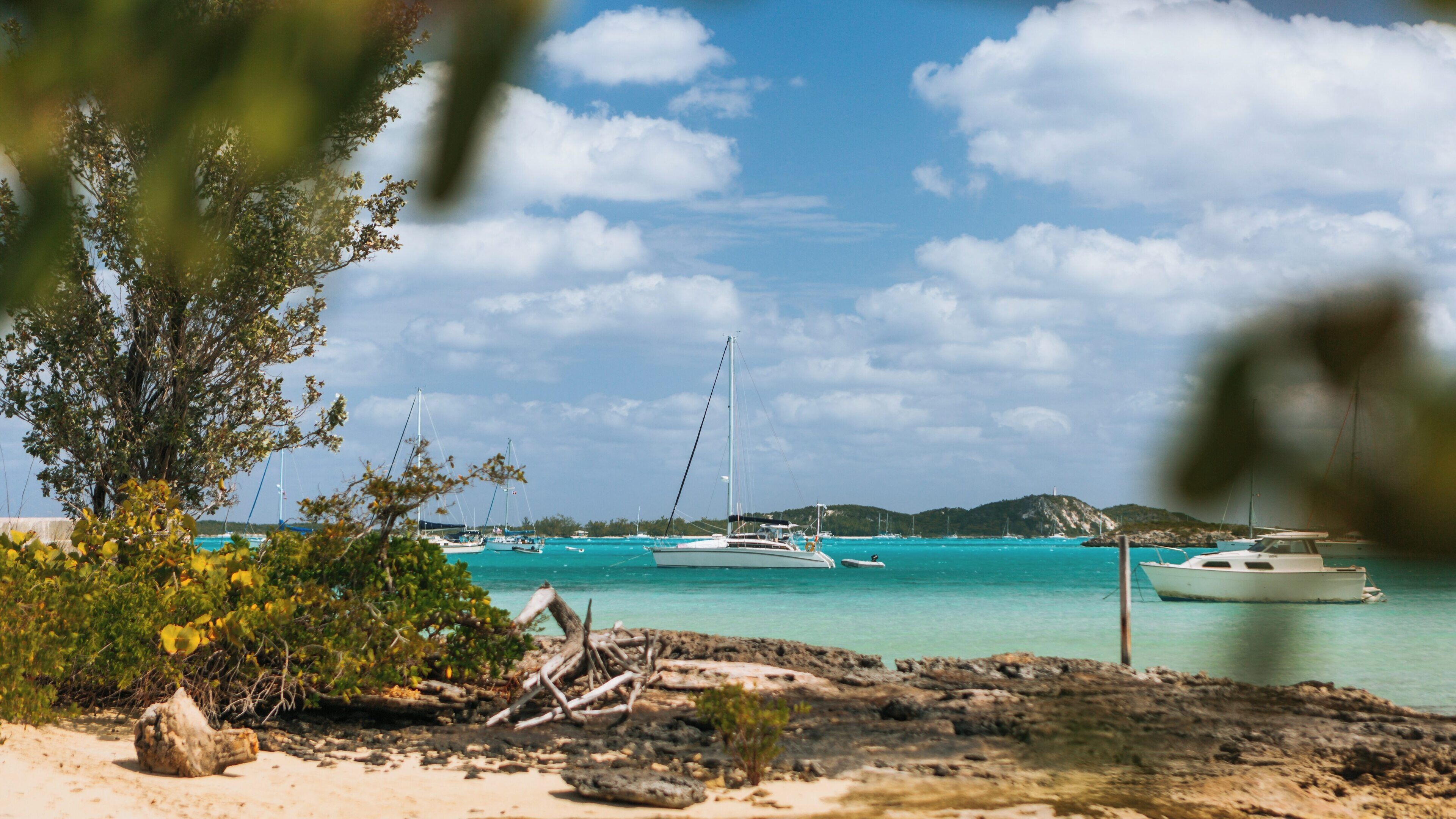 Stunning view of Palm Bay Beach in George Town, Exuma, Bahamas capturing boats in turquoise waters under a blue sky with puffy clouds