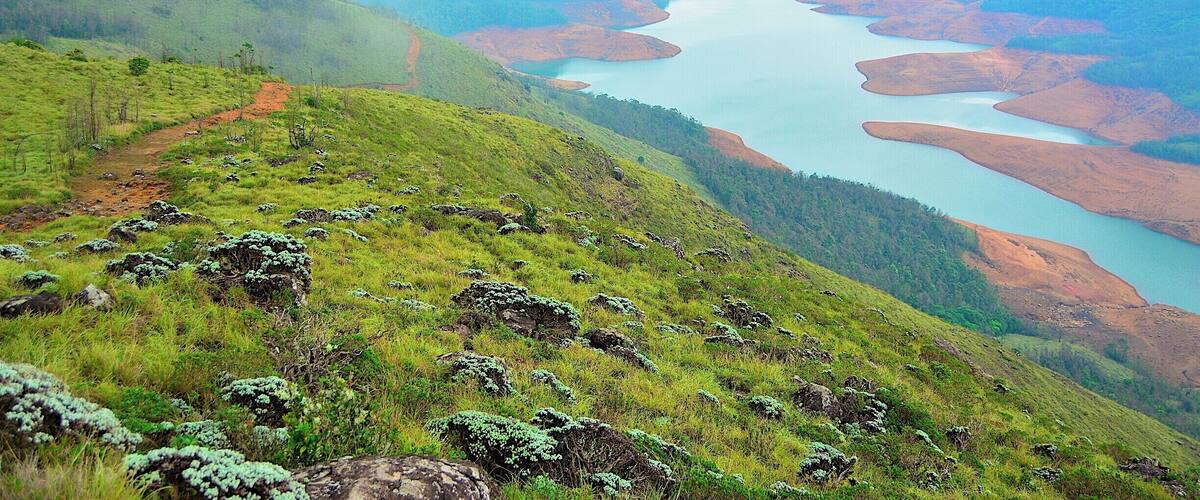 A river winding through a hilly landscape with patches of red earth and green vegetation.