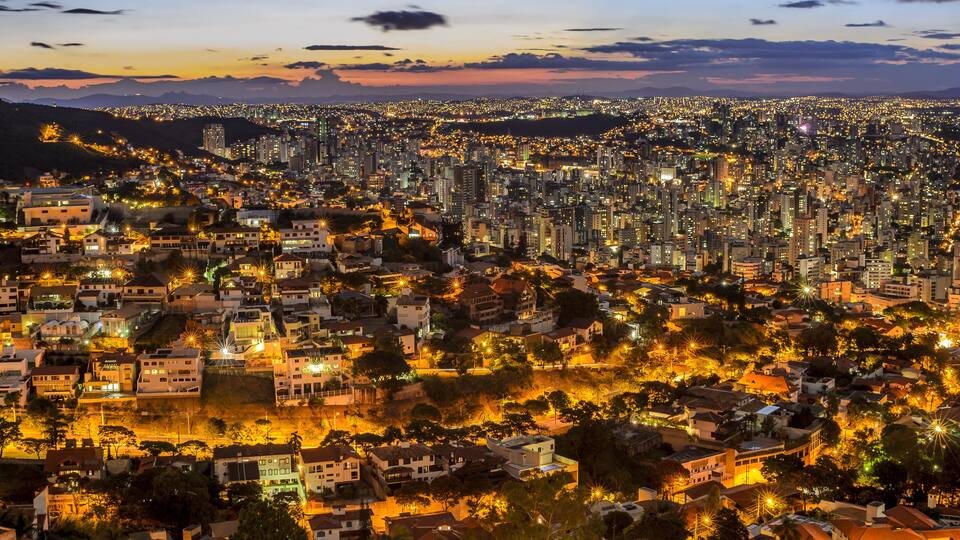 A densely populated cityscape at dusk with numerous illuminated buildings and streets.