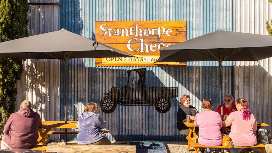 Zona de estar al aire libre de Stanhorpe Cheese con mesas de madera y sombrillas.