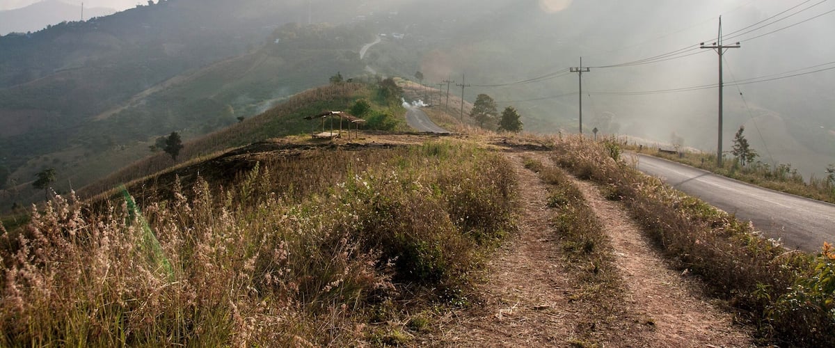 A rural road winding through a hilly landscape with a misty atmosphere.