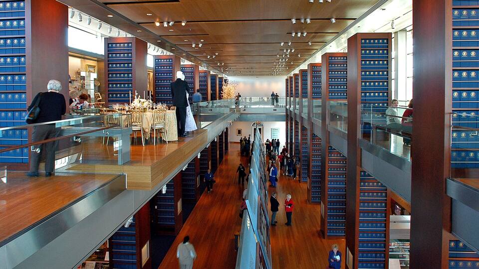 Une bibliothèque à plusieurs niveaux, dotée de planchers en bois et d’étagères bleues.
