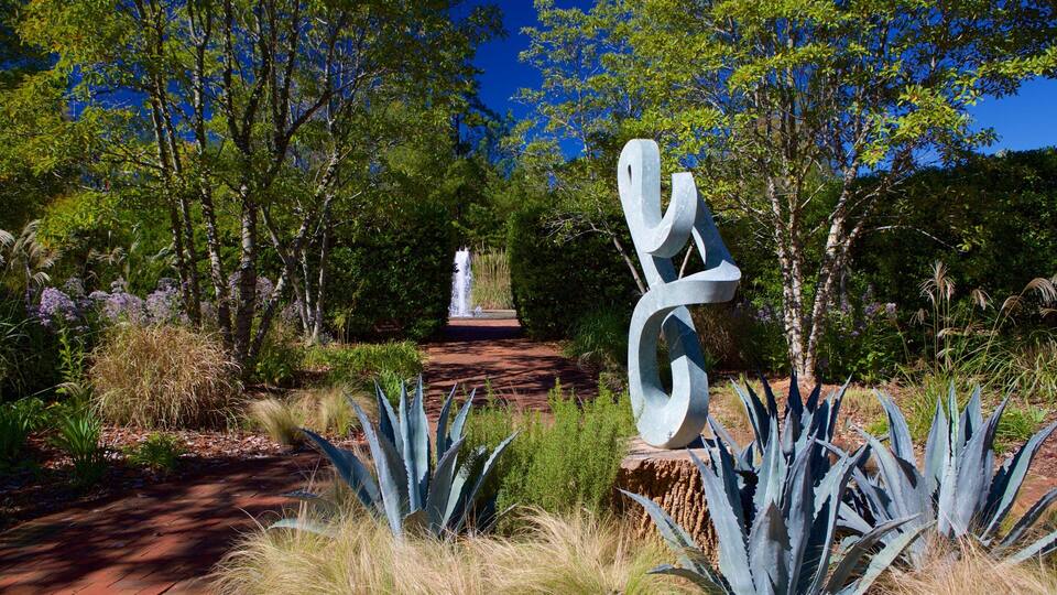 A sculpture in a garden with a pathway leading to a fountain.