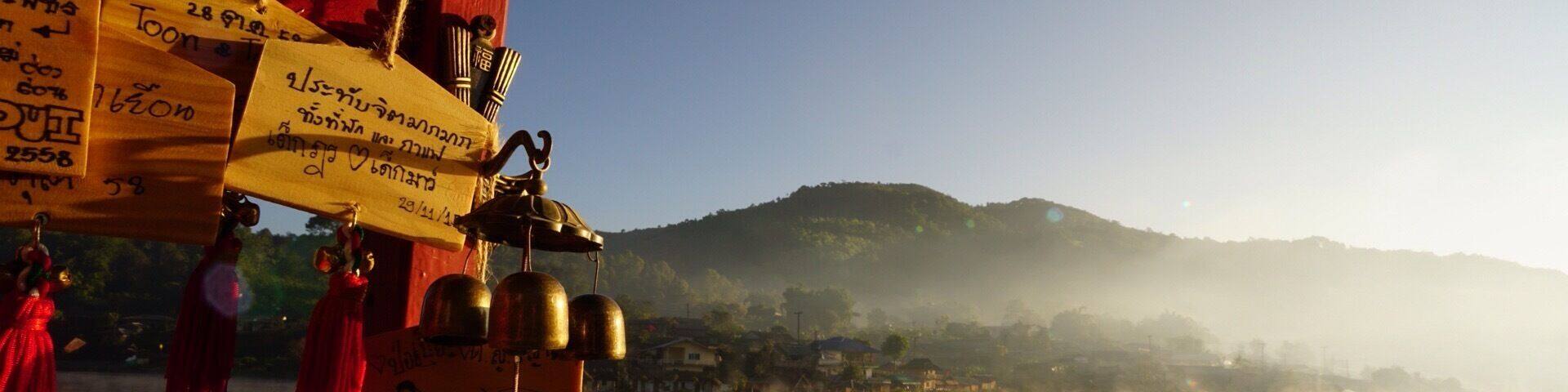 A mountainous landscape with mist and a red structure with inscriptions.