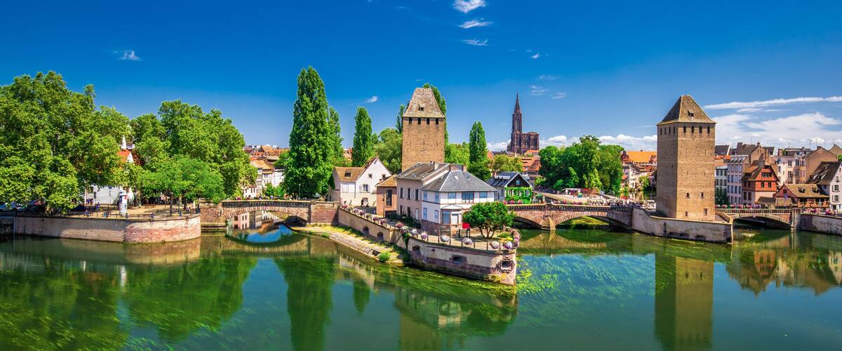 A river with bridges, historic buildings, and a prominent tower.