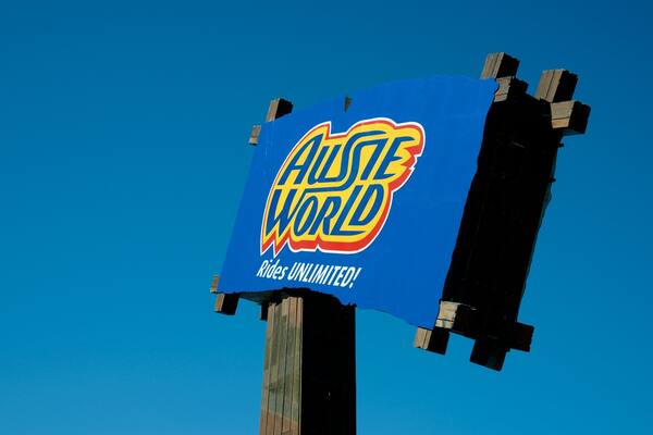 Un panneau bleu sur lequel on peut lire « Austie World » et « Rides Unlimited! », le tout sur fond de ciel bleu clair.