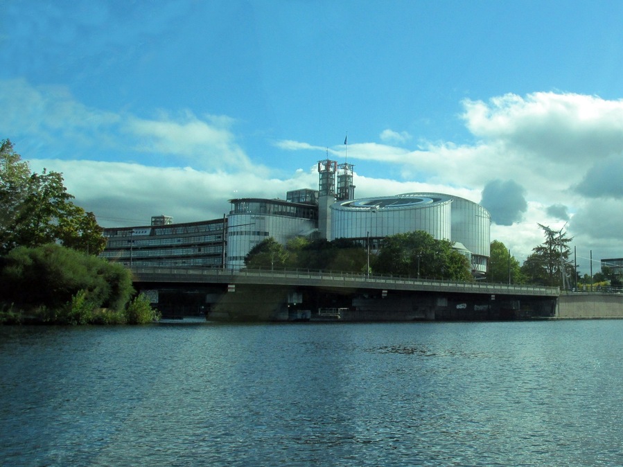 Ein modernes Industriegebäude an einem Fluss, mit einer Brücke darüber.