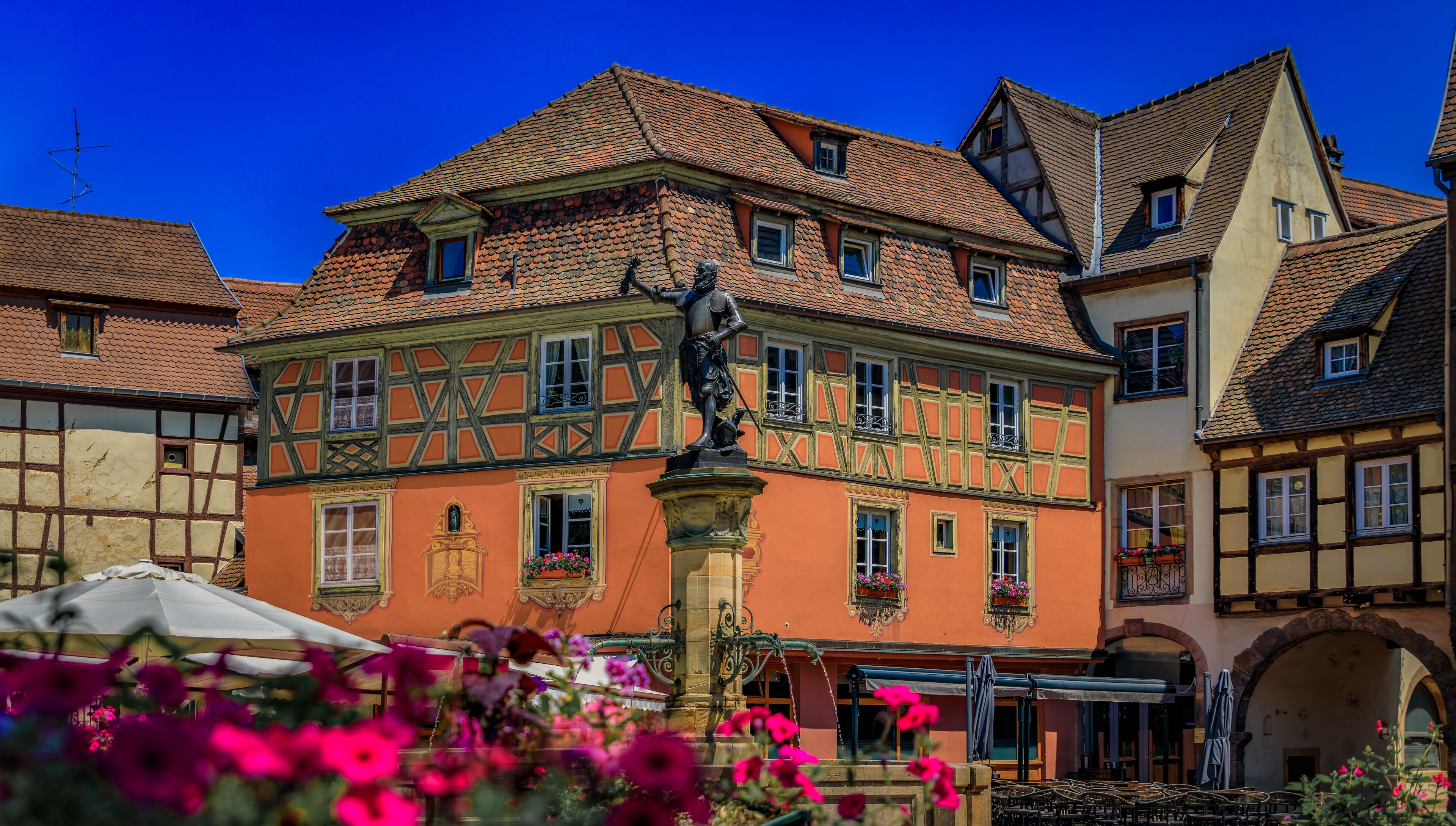 Ornate half timbered houses with blooming flowers near the Schwendi Fountain, Little Venice district in Colmar, picturesque village in Alsace, France