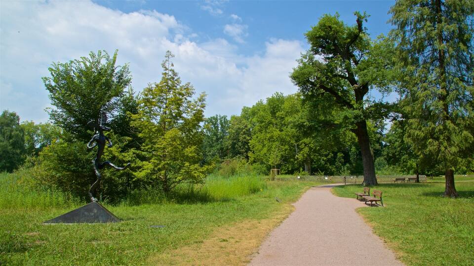 A park with a paved path, benches, and a sculpture.