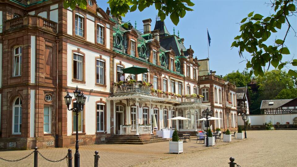 A historic building with ornate architecture, a courtyard with outdoor seating, and a flagpole with a flag.