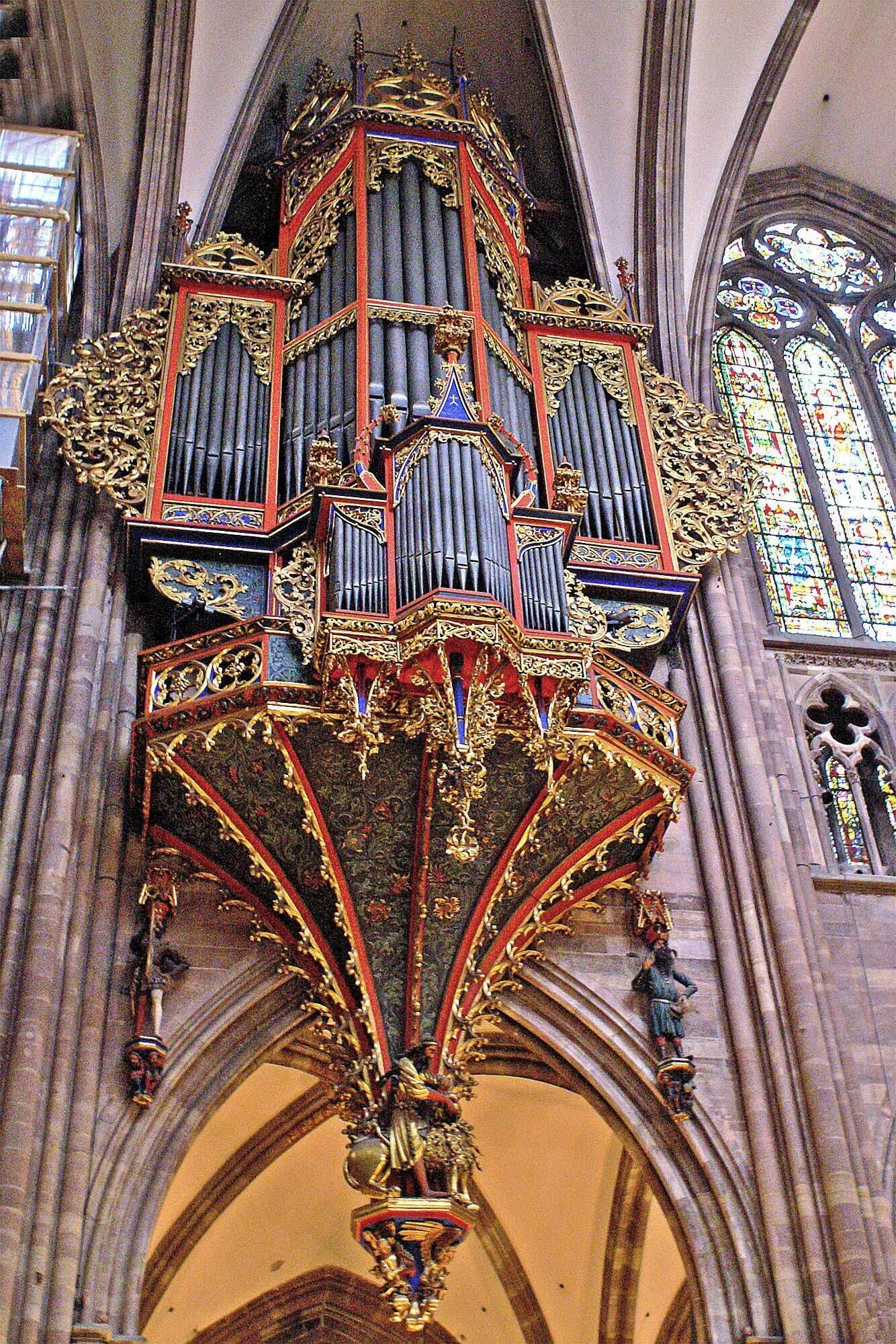 An ornate pipe organ with intricate carvings and a large, decorative grille.