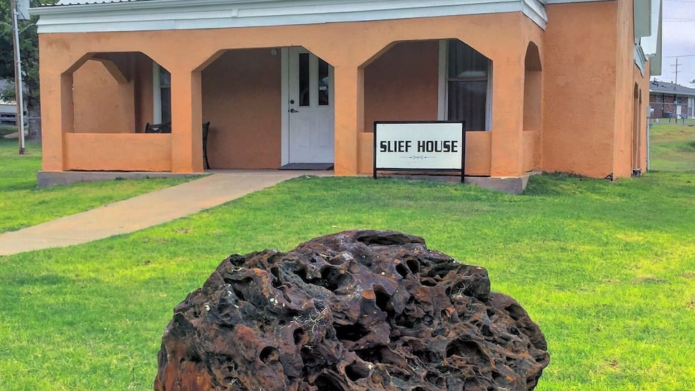 Ein Gebäude mit der Aufschrift 'SLIEF HOUSE' und einer einzigartigen Felsenskulptur davor.