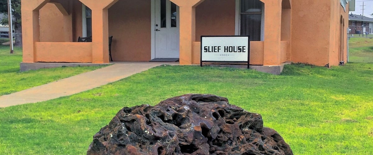 A building labeled 'SLIEF HOUSE' with a unique rock sculpture in front.