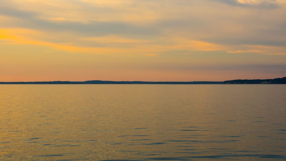 A calm body of water reflecting the sky during sunset.