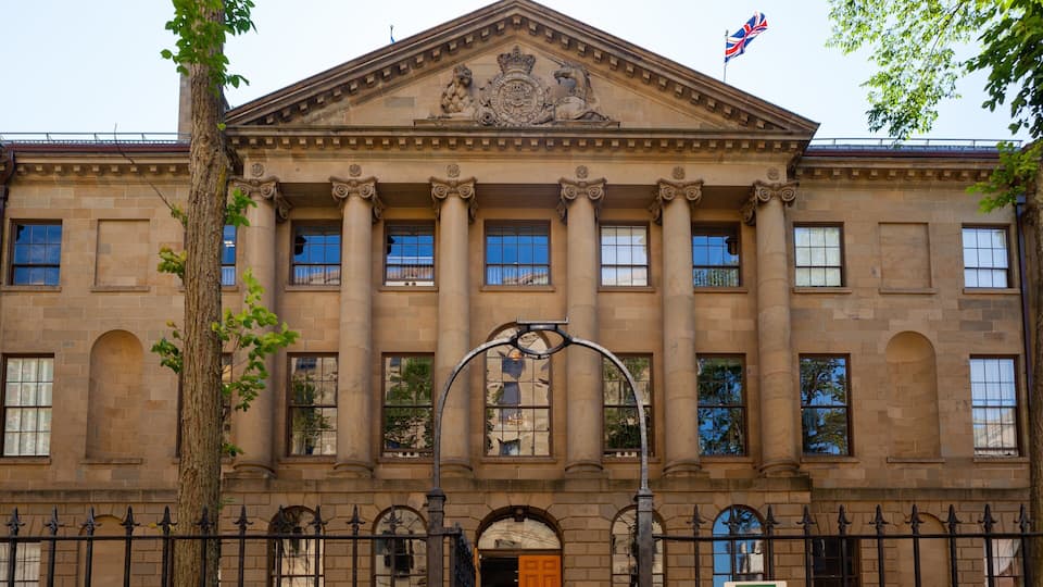 Un gran edificio de piedra con columnas, un escudo y una bandera.