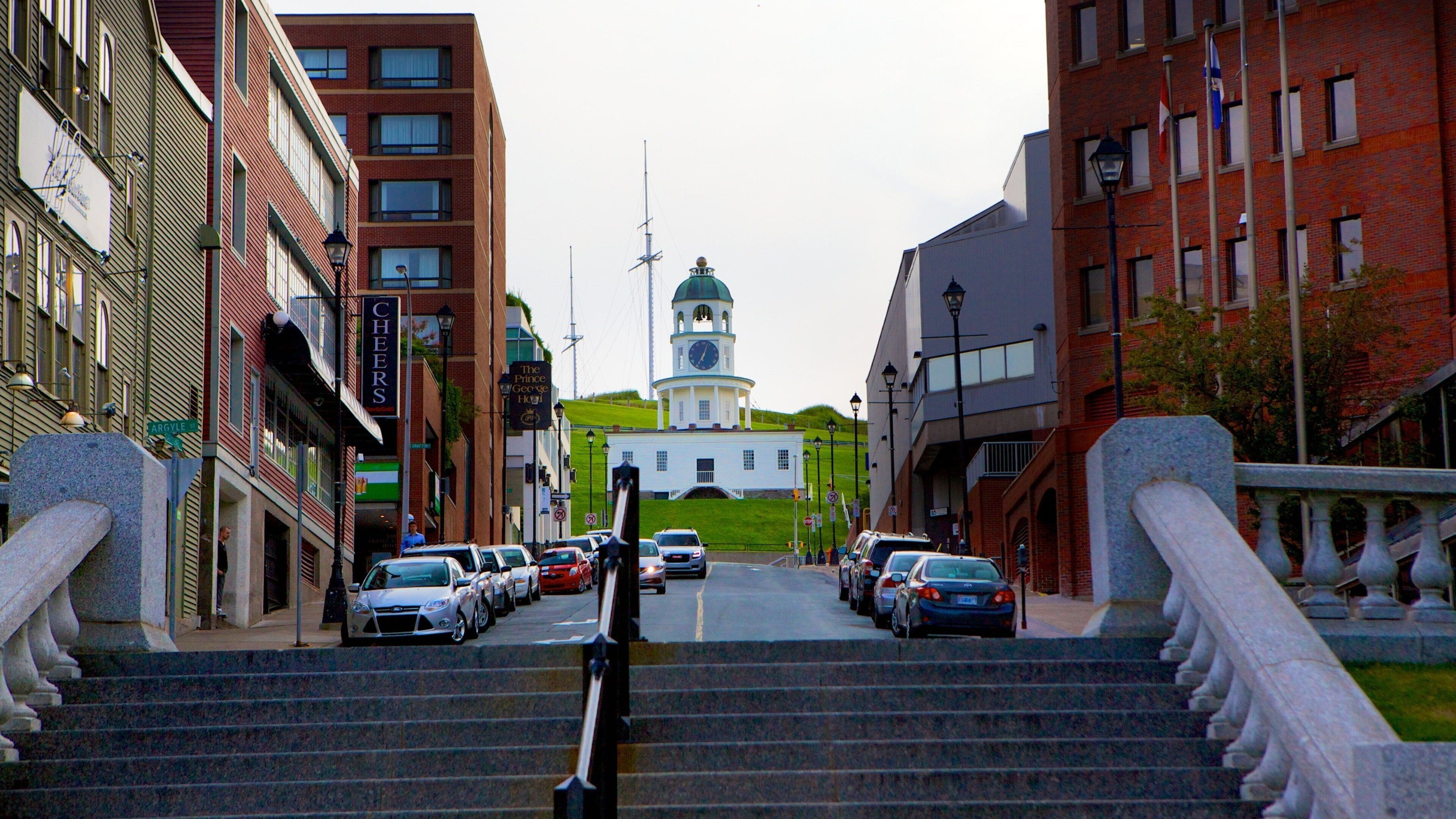 A street leading to a white building with a clock tower.