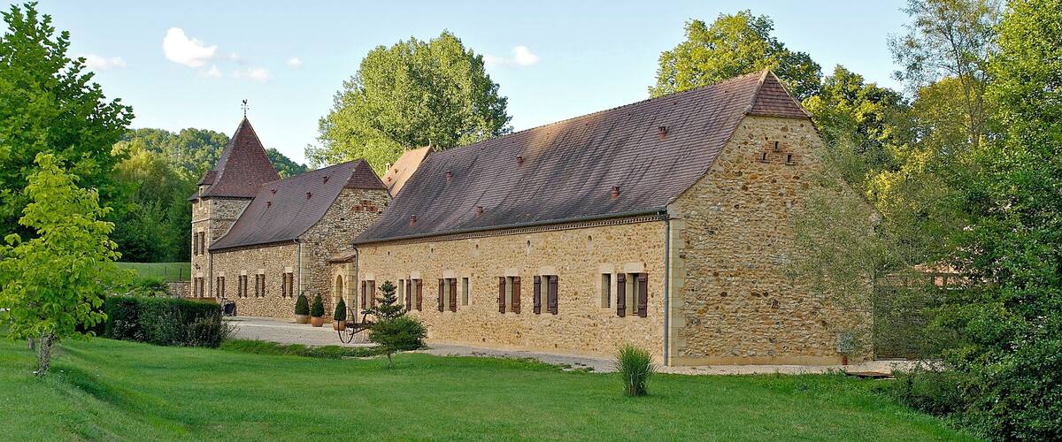 A stone building with a tiled roof and a small tower.