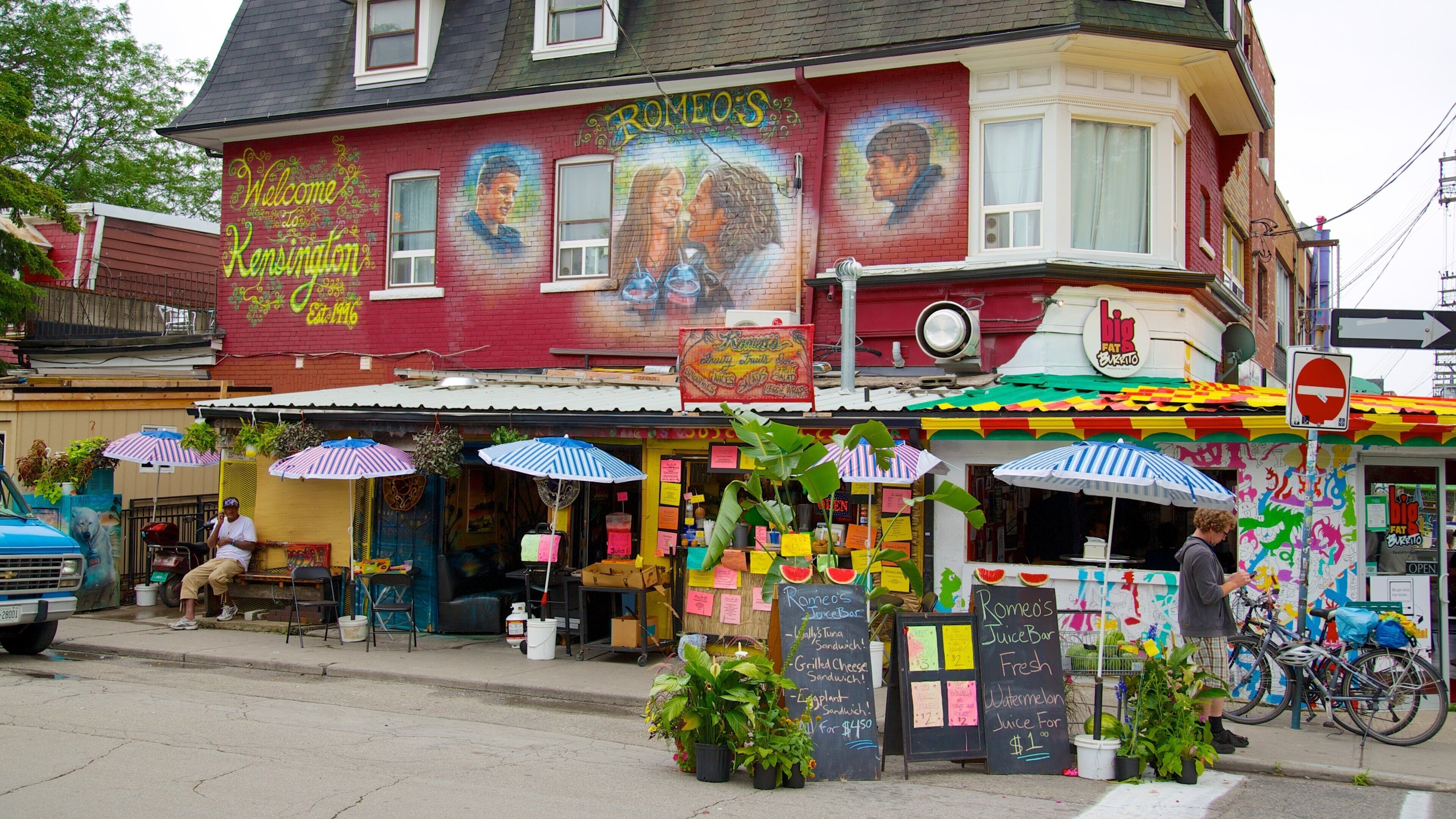 A colorful building with a mural, outdoor seating, and a juice bar.