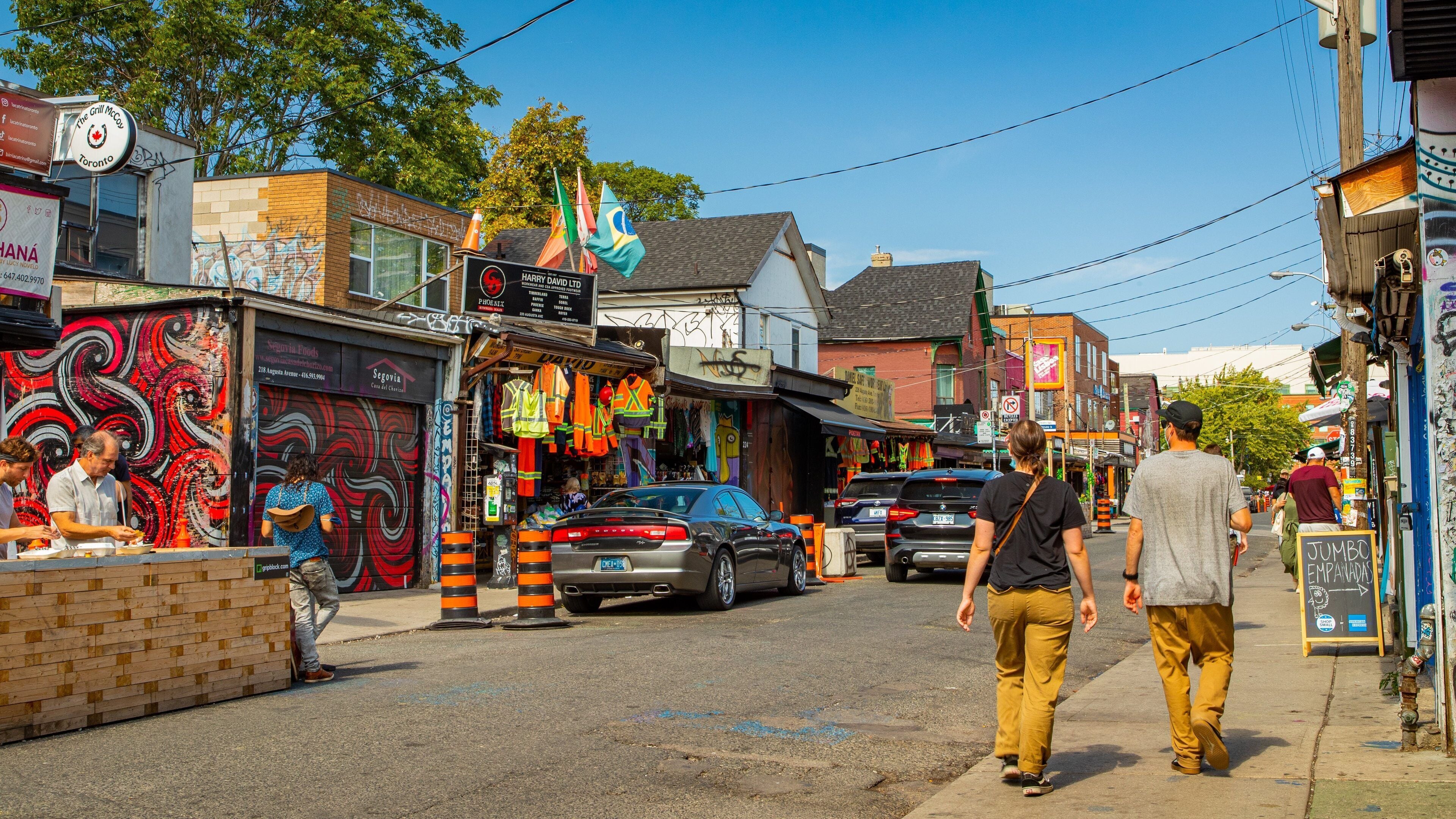 A street with shops, a mural, and a car.
