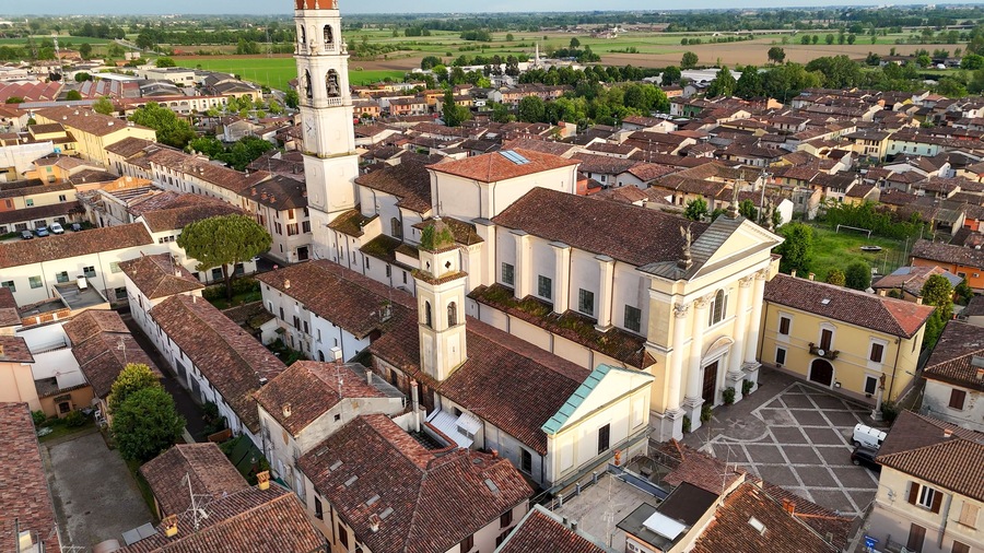 Aerial view capturing Pontevico village in Brescia province, revealing Parish Church of Santa Maria Assunta nestled among terracotta rooftops and verdant countryside landscape