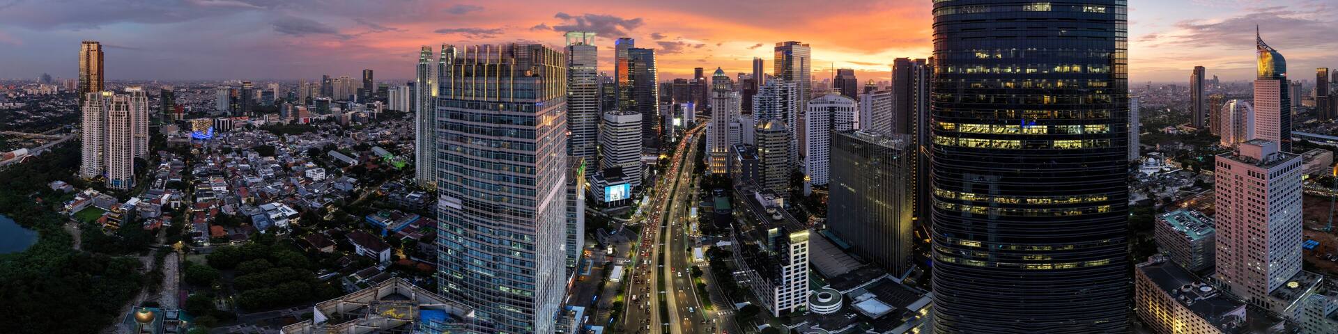A cityscape with tall buildings, a river, and a sunset.