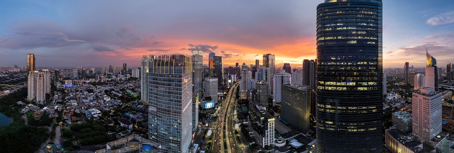 A cityscape with tall buildings, a river, and a sunset.