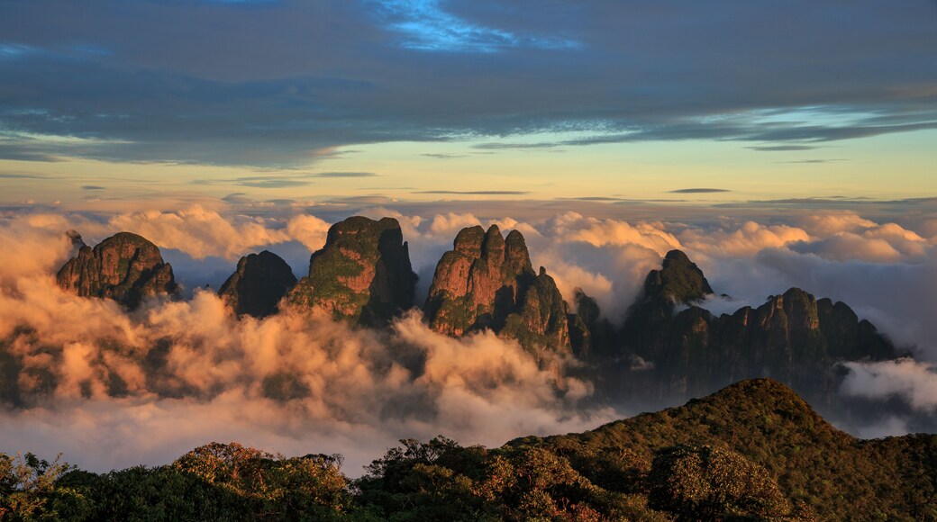 A mountainous landscape with prominent rock formations surrounded by clouds.