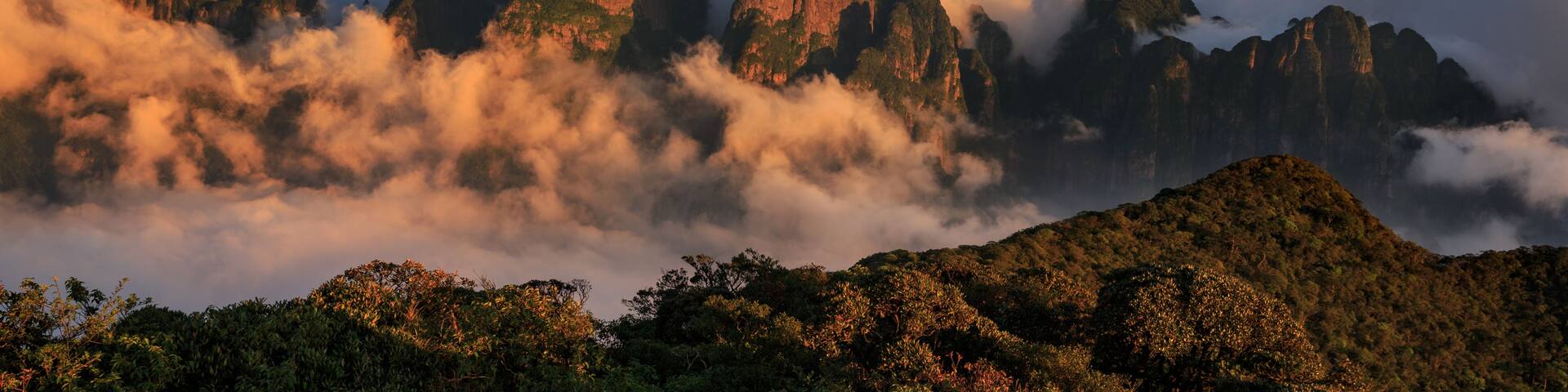 A mountainous landscape with prominent rock formations surrounded by clouds.