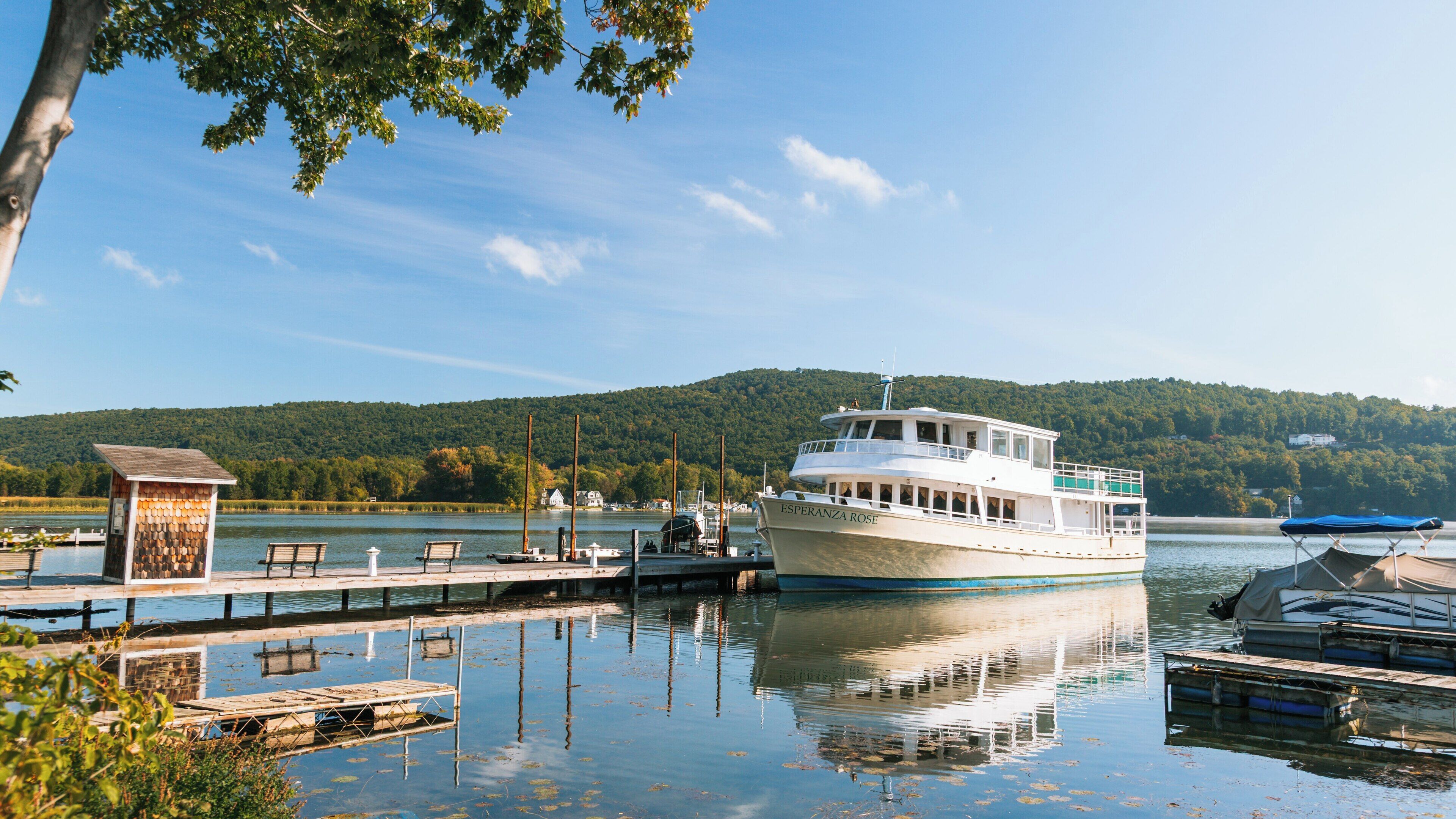 Cruise boat docked at Keuka Lake State Park in Keuka Park, New York during a clear day with reflections on calm water