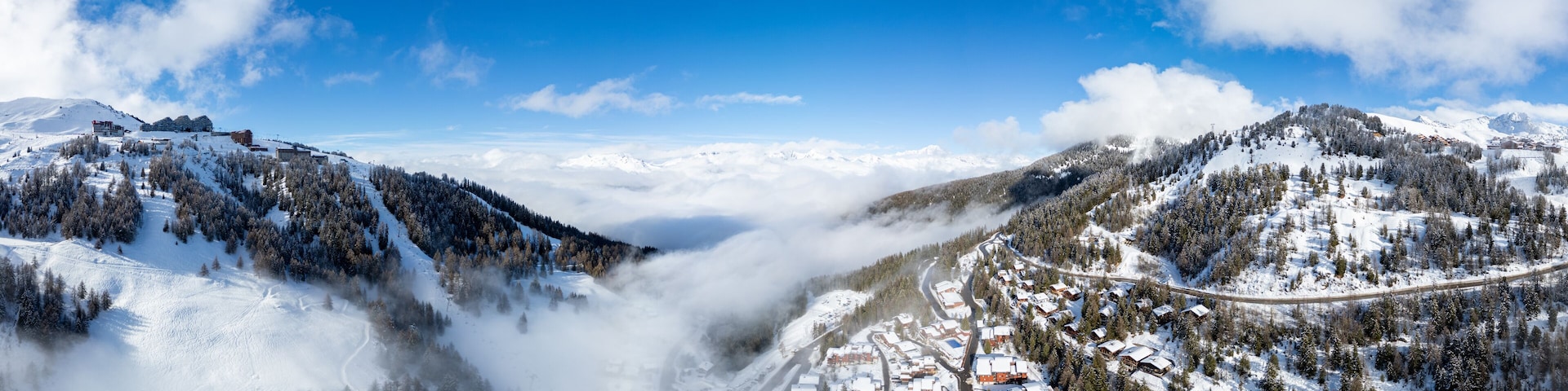 A snow-covered mountain village with a winding road and dense forests.