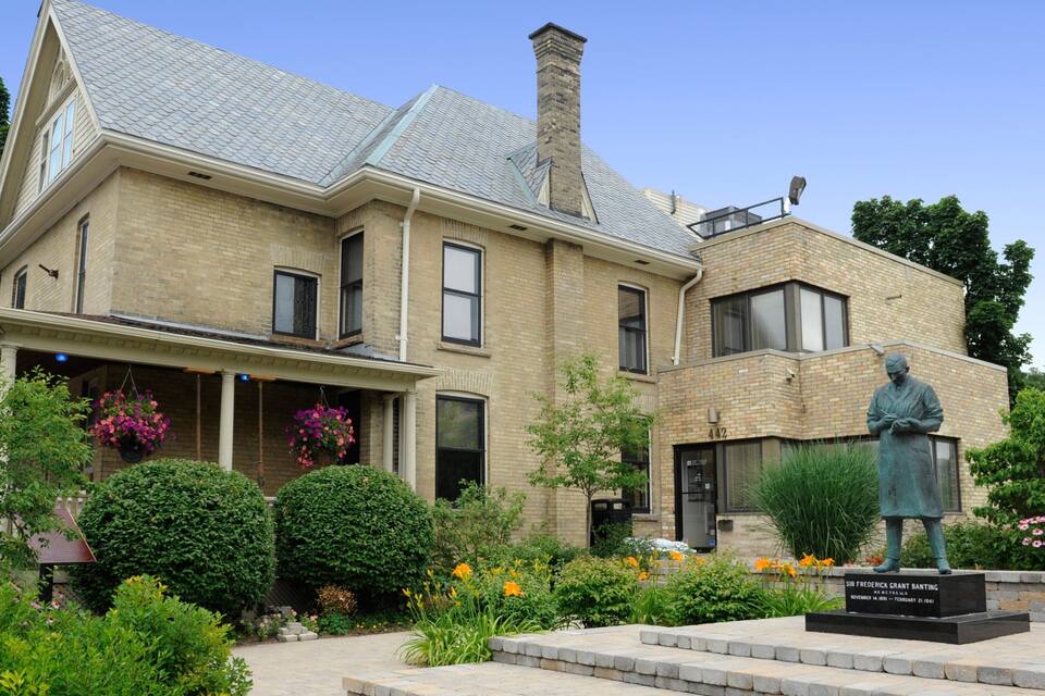 Una casa històrica amb una estàtua de Sir Frederick Grant Banting a la façana.