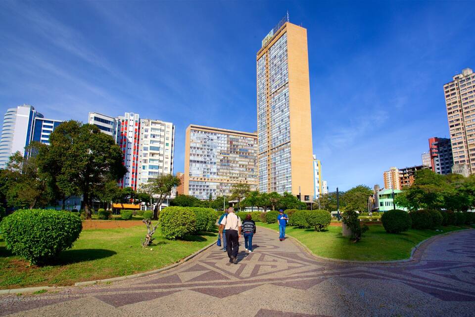A cityscape with tall buildings, a clear blue sky, and a park with walking paths.